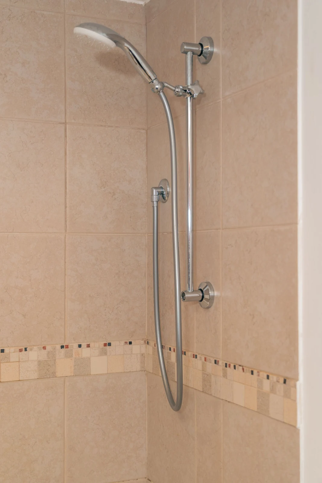 Hand shower against beige bathroom tiles