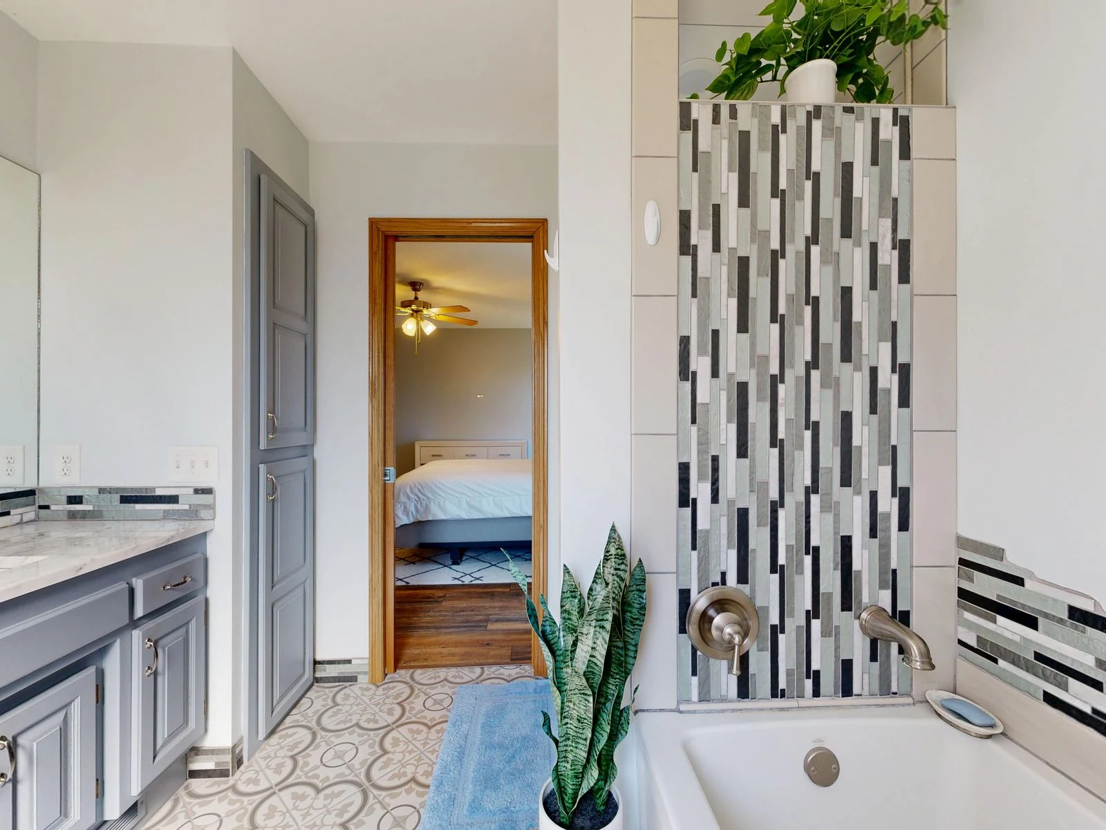 Stylish bathroom with tiled shower and view into a cozy bedroom