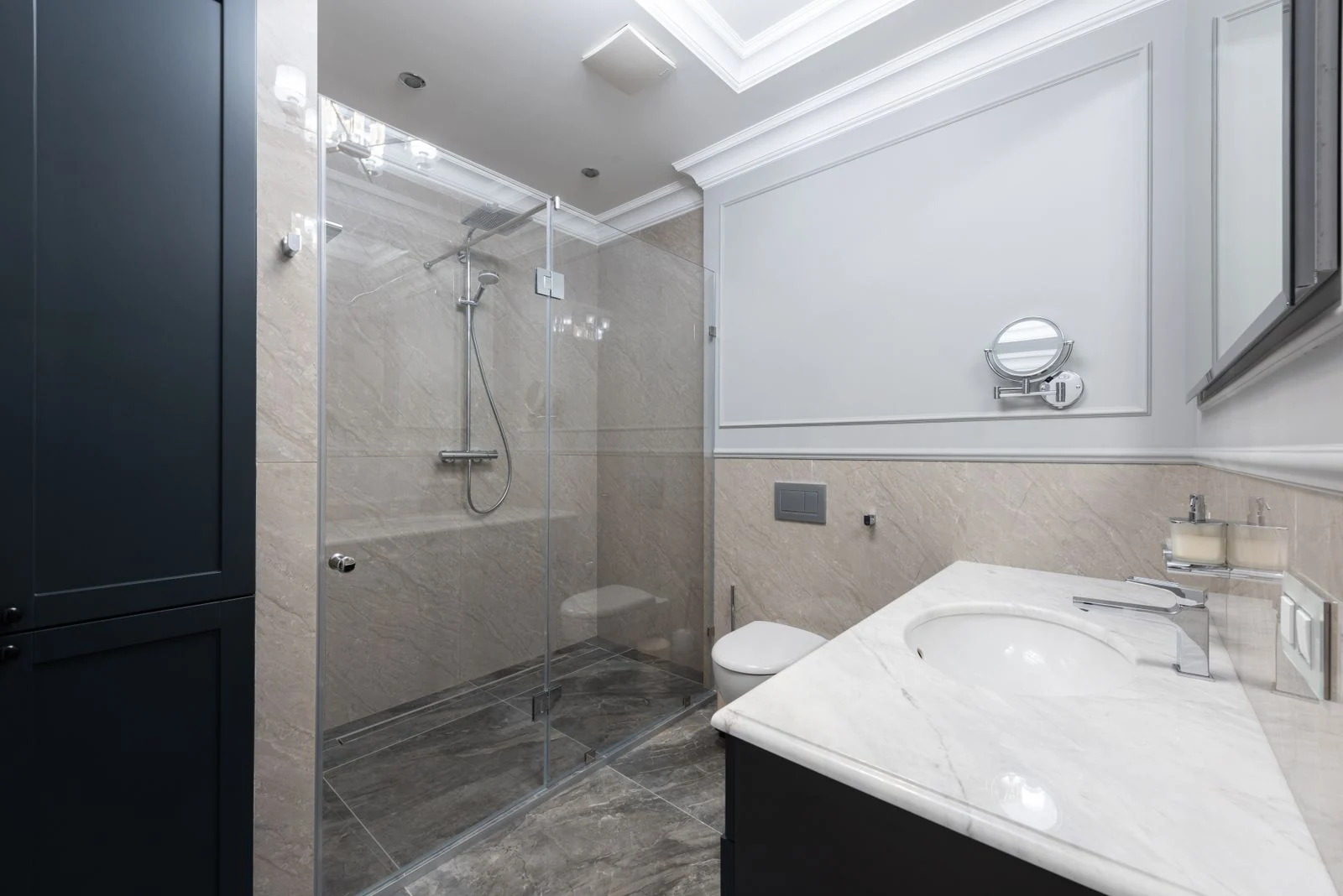 Contemporary spacious bathroom with convenient glass shower illuminated with bright light of lamps