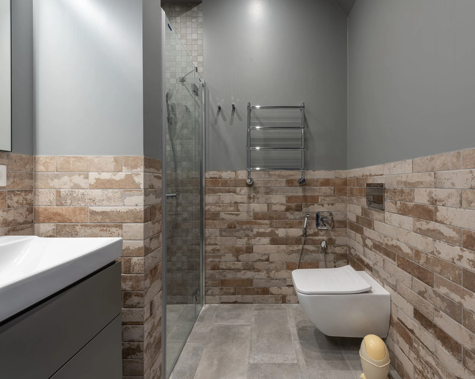 Stylish contemporary bathroom featuring a glass shower and brick accent wall